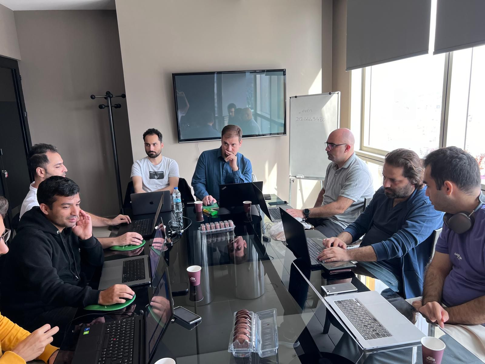 “Some team members at Blue Coder Solutions working together around a table with their laptops during a meeting.”